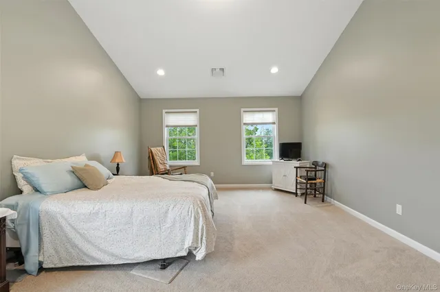 a bedroom with a bed chair and two windows