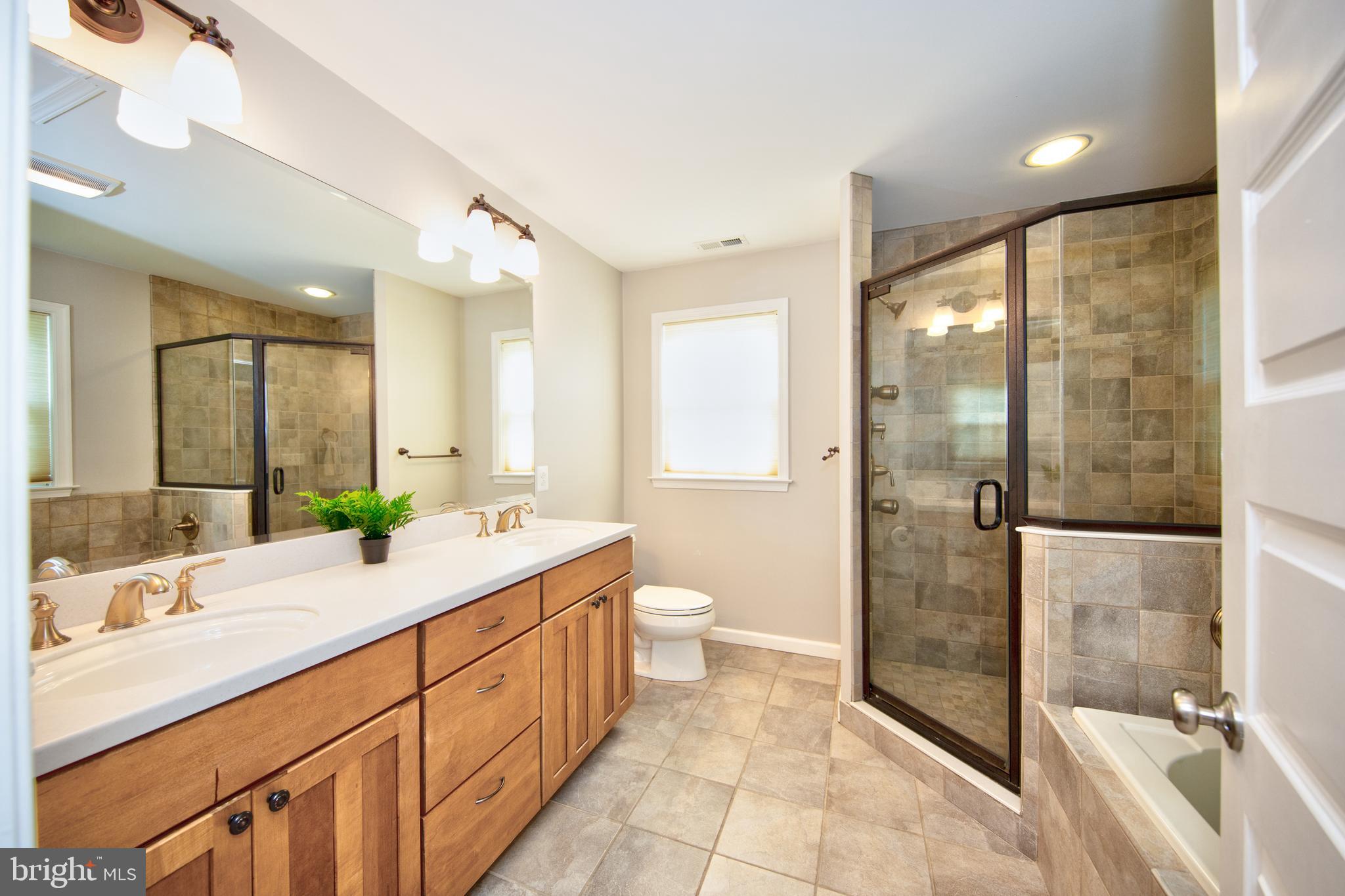 9315 Perglen Road Baltimore, MD 21236 - Photo 14 of 32 a spacious bathroom with a double vanity sink toilet mirror and shower