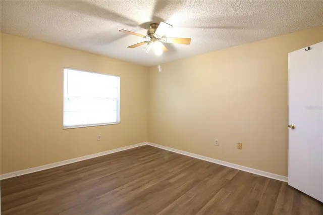 an empty room with wooden floor and fan