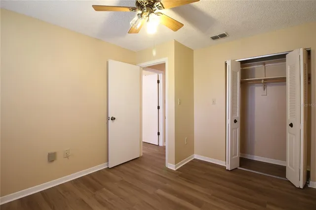 an empty room with wooden floor and a ceiling fan