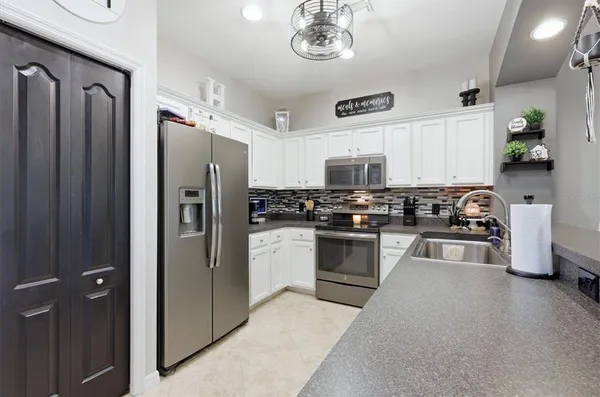a kitchen with granite countertop a refrigerator a stove a sink and cabinets