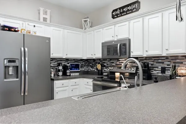a kitchen with stainless steel appliances a stove a sink a refrigerator a cabinets and a counter space