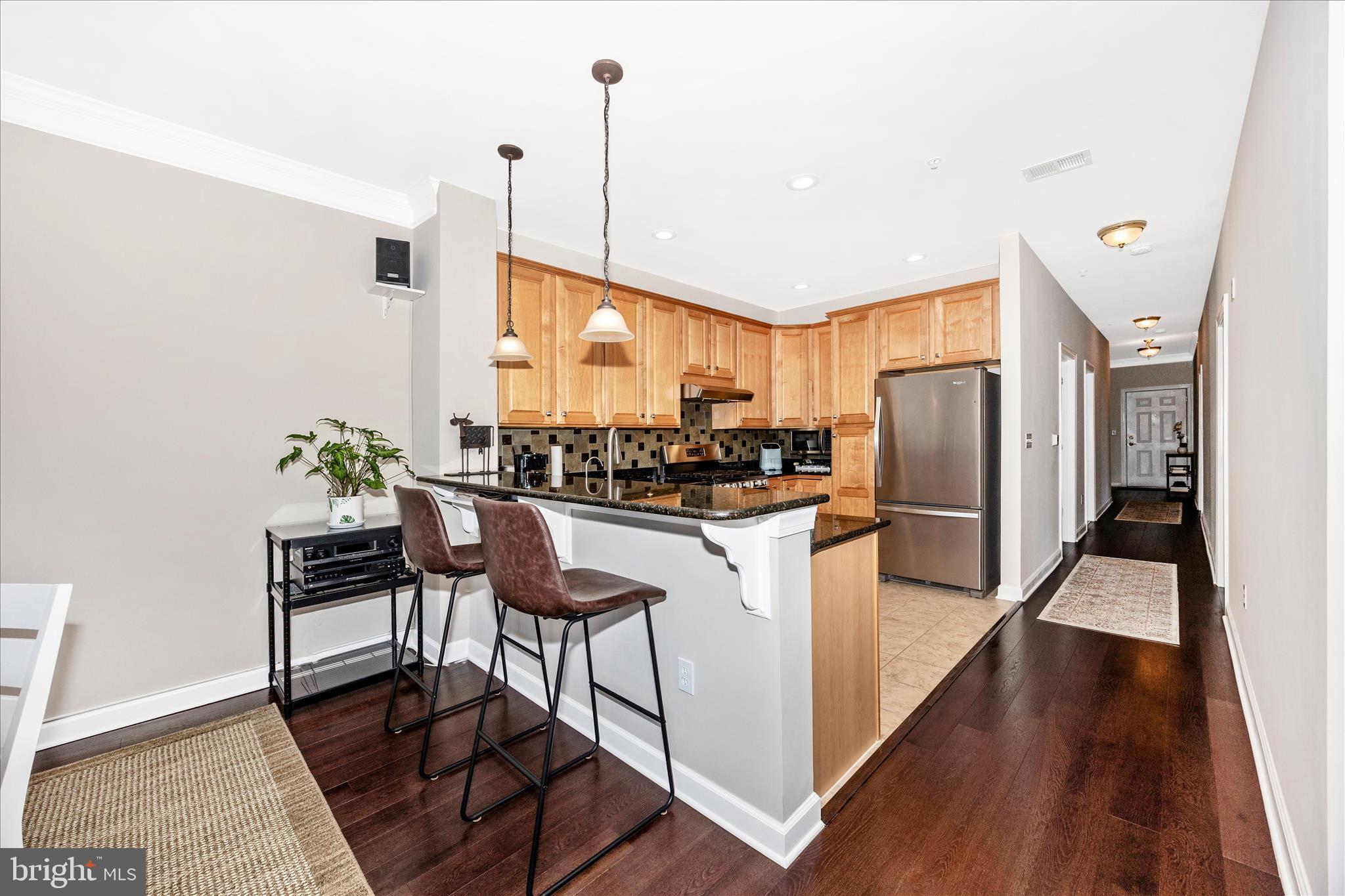 35 East All Saints Street, Unit 211 Frederick, MD 21701 - Photo 27 of 61 a kitchen with stainless steel appliances a refrigerator a stove a sink and a dining table with wooden floor