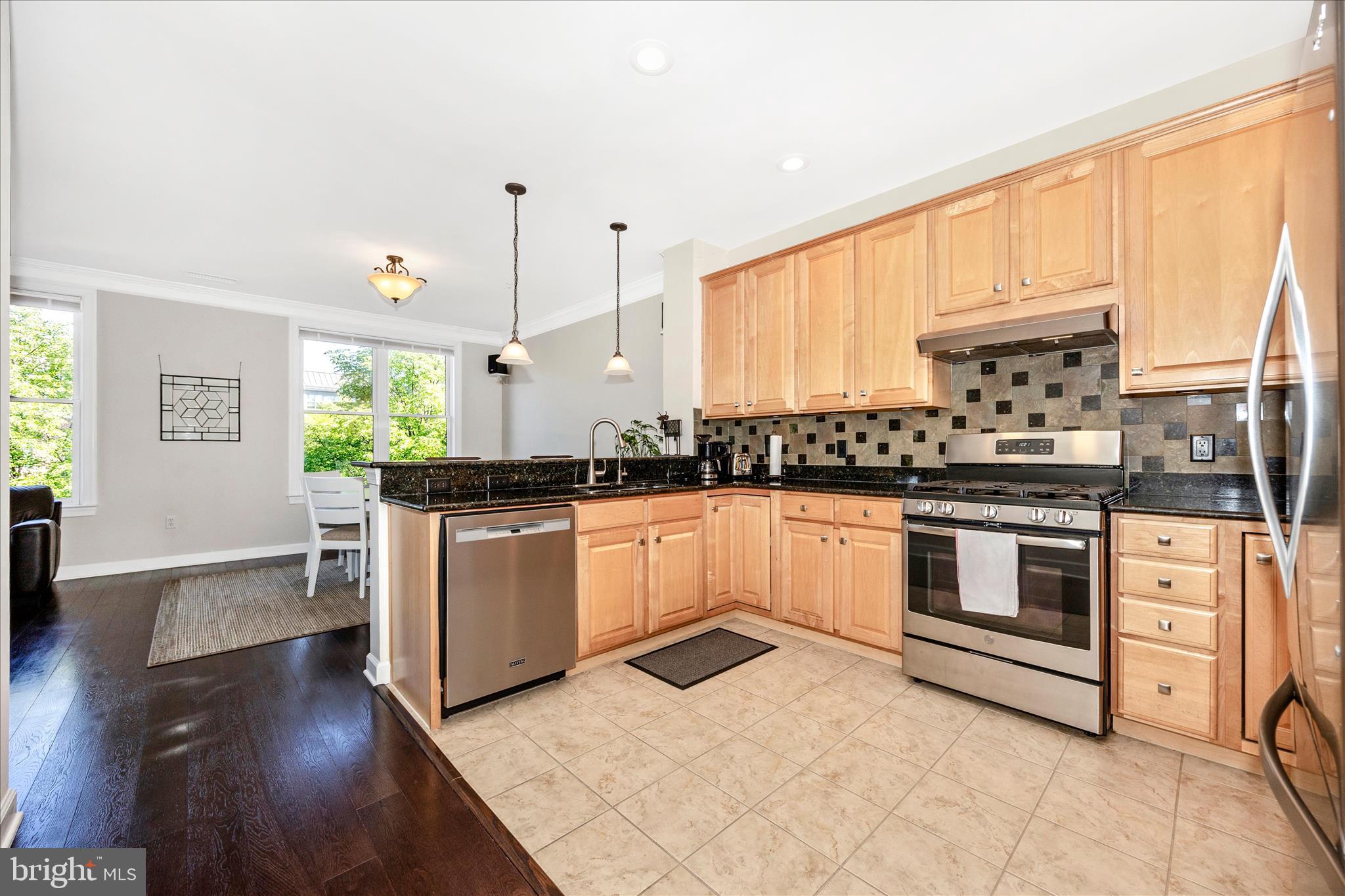 35 East All Saints Street, Unit 211 Frederick, MD 21701 - Photo 30 of 61 a kitchen with stainless steel appliances kitchen island granite countertop a stove a sink and white cabinets with wooden floor