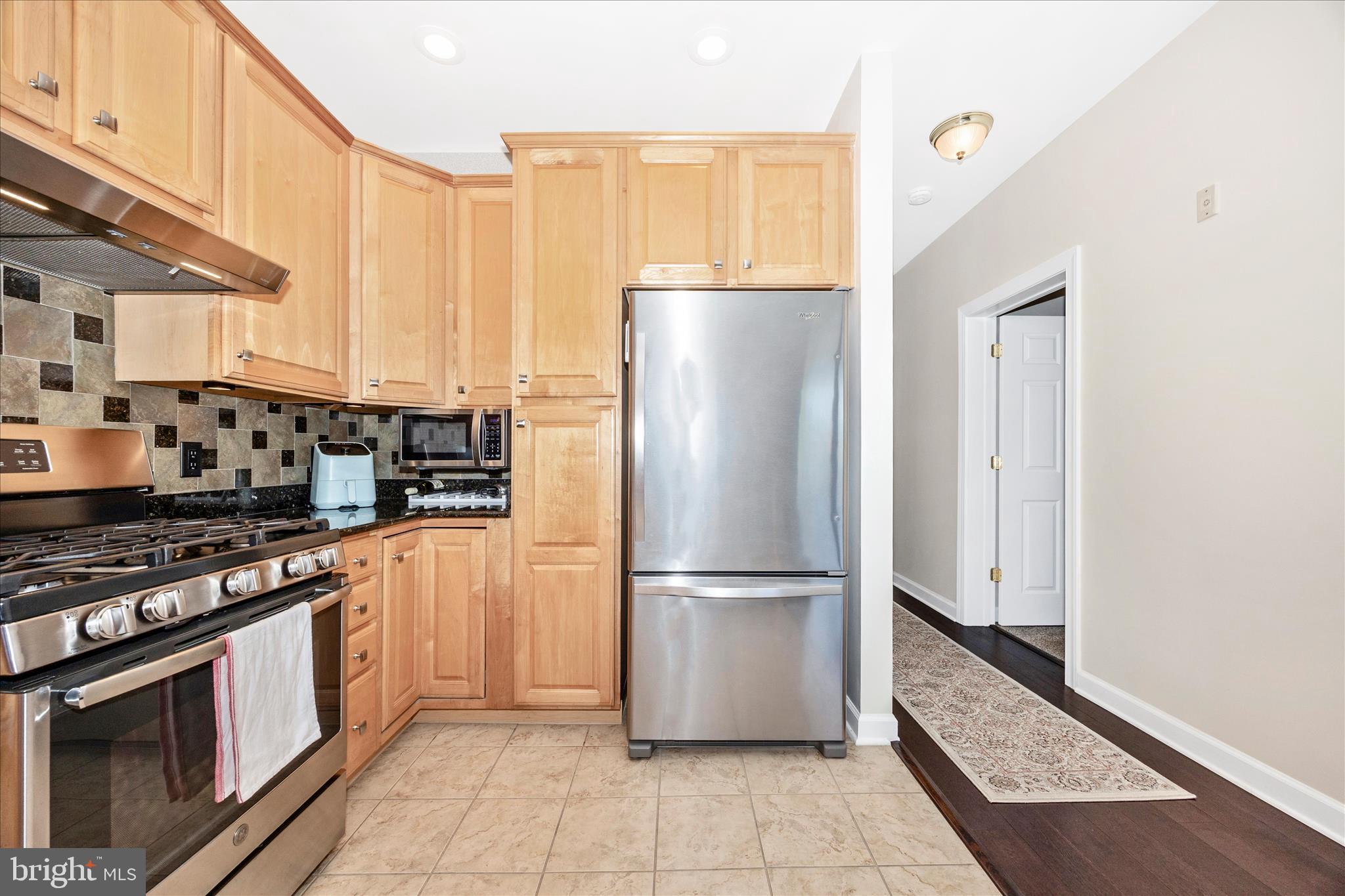 35 East All Saints Street, Unit 211 Frederick, MD 21701 - Photo 32 of 61 a kitchen with stainless steel appliances granite countertop a refrigerator a stove and a sink with wooden floor