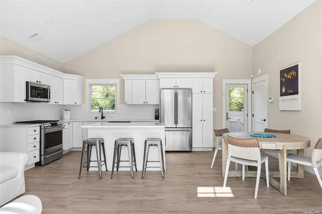 a kitchen with stainless steel appliances granite countertop a dining table chairs refrigerator a sink dishwasher and a stove