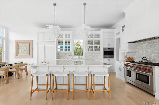 a kitchen with stainless steel appliances kitchen island granite countertop a table chairs stove and white cabinets