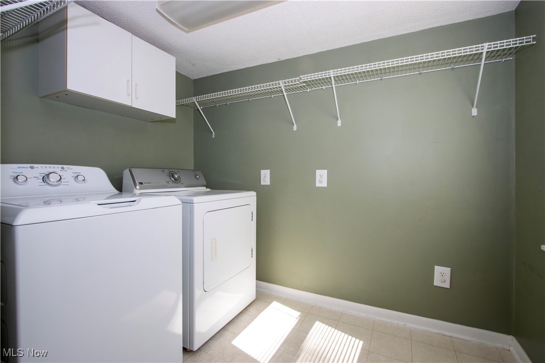 7210 Cleveland Road Wooster, OH 44691 - Photo 10 of 22 Washroom with cabinet space, washing machine and clothes dryer, light tile patterned flooring, and a textured ceiling