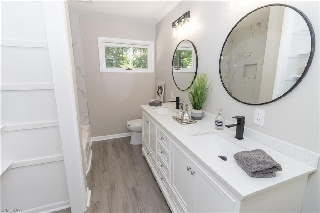 2216 Lane Road Greensboro, NC 27408 - Photo 11 of 38 BATHROOM: THIS ROOM WAS RENOVATED. NEW CABINETS, COUNTER TOP, FAUCETS, MIRRIORS AND LIGHTS, TUB SURROUND, LVT FLOORING AND OPEN SHELVING.