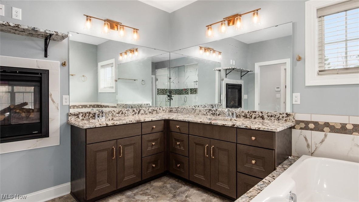4641 Foote Road Medina, OH 44256 - Photo 25 of 46 Full bath with a multi sided fireplace, double vanity, a garden tub, and a stall shower