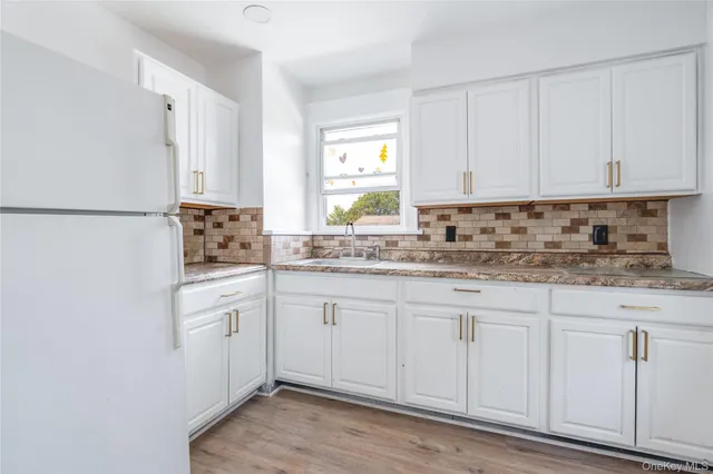 a kitchen with granite countertop white cabinets white appliances a sink and a window