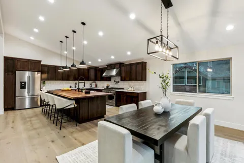 a kitchen with stainless steel appliances granite countertop a sink a stove a kitchen island with chairs and white cabinets