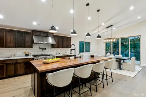 a kitchen with stainless steel appliances granite countertop a stove a sink a microwave a center island and chairs