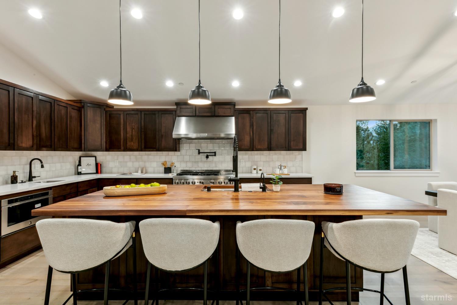 2051 Nez Perce Drive South Lake Tahoe, CA 96150 - Photo 15 of 40 a kitchen with stainless steel appliances granite countertop a sink a stove a kitchen island with chairs and white cabinets