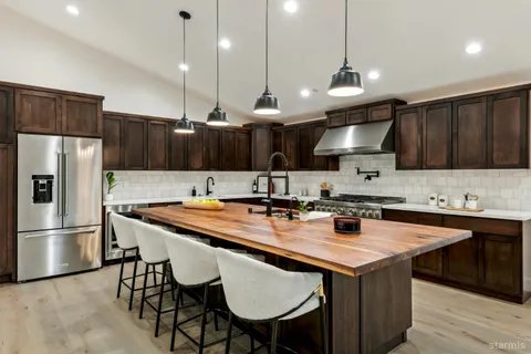 a kitchen with granite countertop a sink a center island stainless steel appliances and cabinets