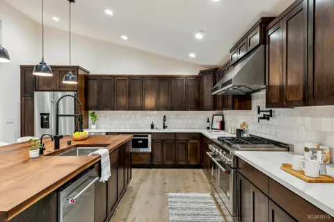 a kitchen with stainless steel appliances granite countertop a sink a stove and a refrigerator