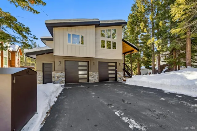 a front view of a house with wooden deck and outdoor seating