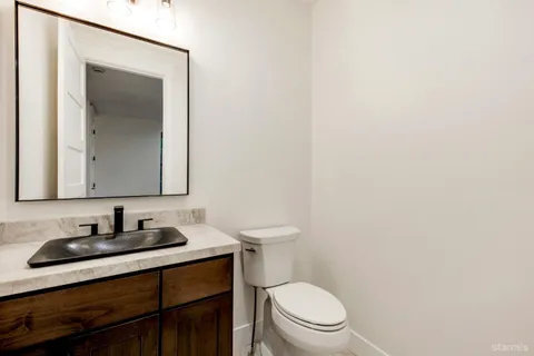 a bathroom with a toilet sink vanity and mirror