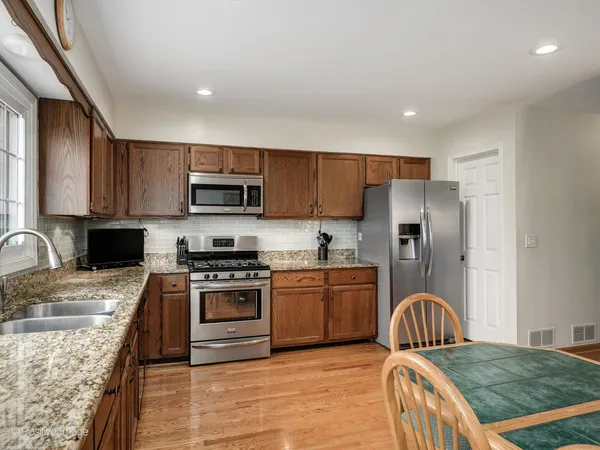 a kitchen with granite countertop a stove top oven a sink dishwasher a dining table and chairs with wooden floor