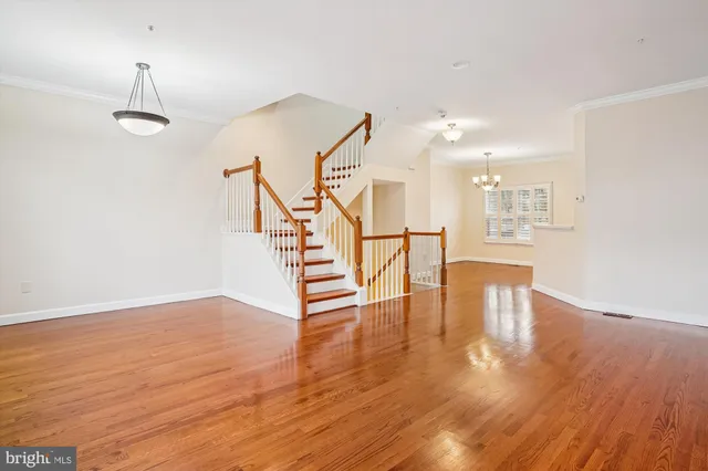 a view of empty room with wooden floor and stairs