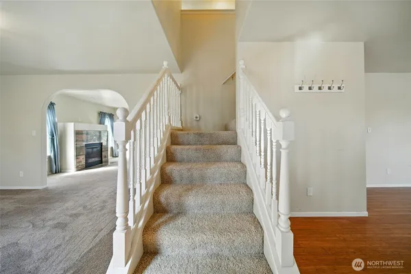 a view of staircase with lots of frames on wall and a dining table