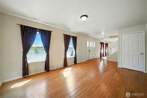 a view of empty room with wooden floor and fan