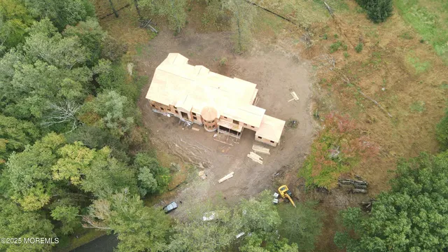 an aerial view of a house with a yard and trees all around