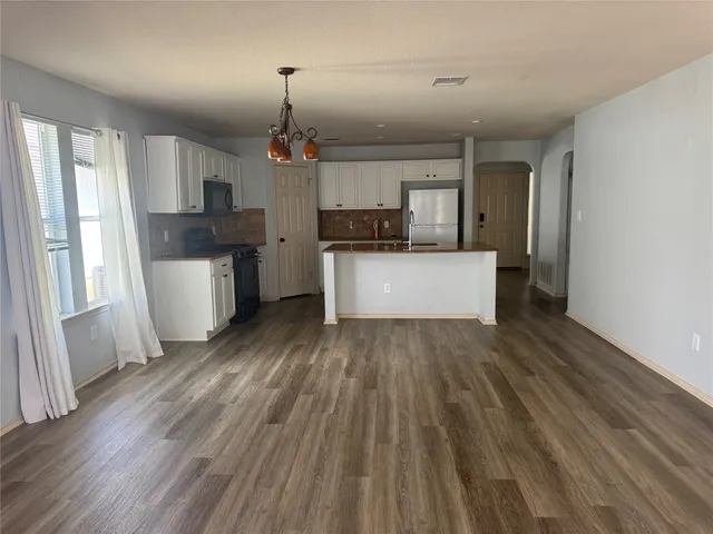 a large kitchen with a wooden floor and stainless steel appliances