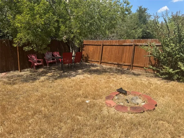 a view of a backyard with large tree and wooden fence
