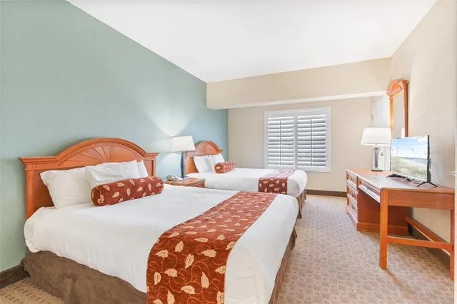 a bedroom with two beds and a potted plant