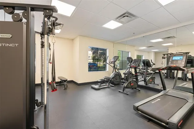 a dining room with wooden floor a chandelier fan a glass table and windows