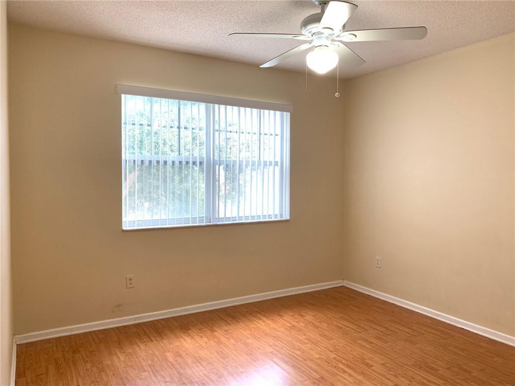 5980 West Sample Road, Unit 303 Coral Springs, FL 33067 - Photo 15 of 32 an empty room with wooden floor fan and windows
