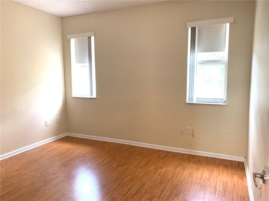 5980 West Sample Road, Unit 303 Coral Springs, FL 33067 - Photo 18 of 32 an empty room with wooden floor and windows