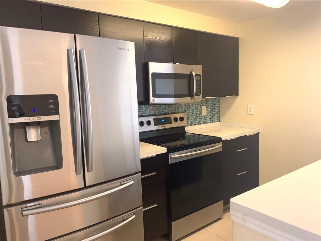 5980 West Sample Road, Unit 303 Coral Springs, FL 33067 - Photo 29 of 32 a kitchen with a refrigerator and a sink