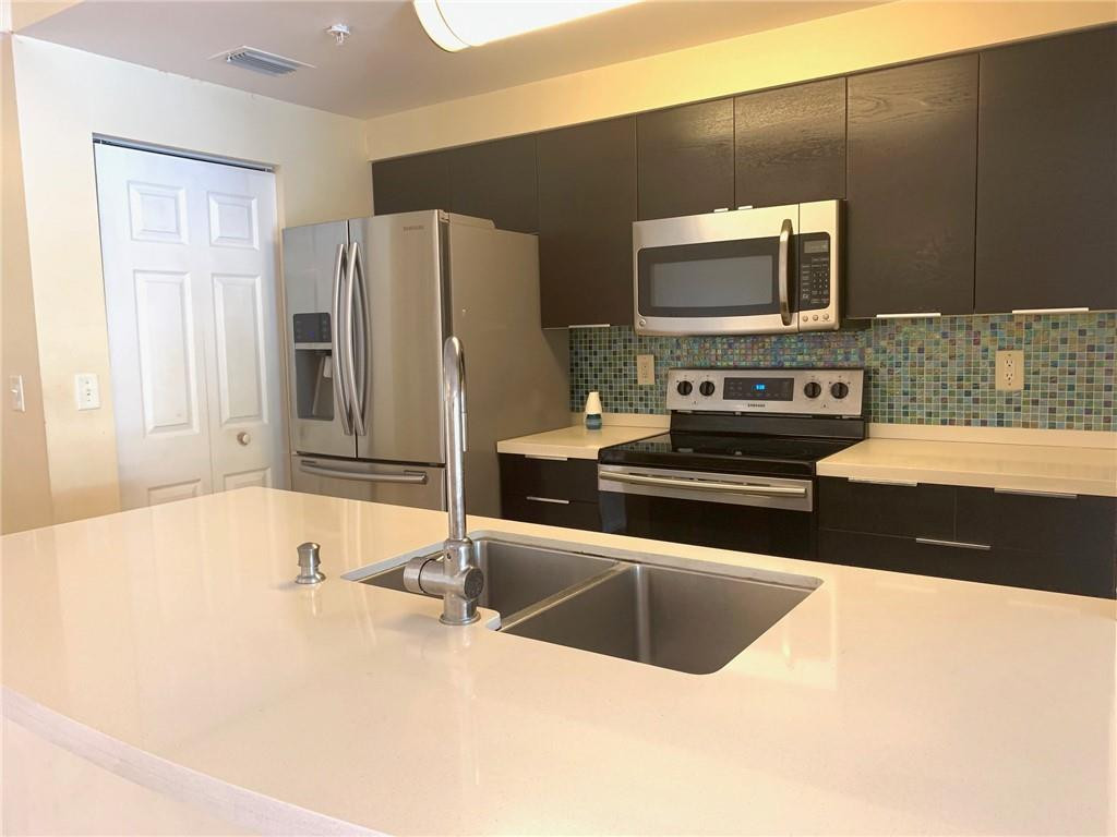 5980 West Sample Road, Unit 303 Coral Springs, FL 33067 - Photo 8 of 32 a kitchen with stainless steel appliances a microwave a stove and a refrigerator