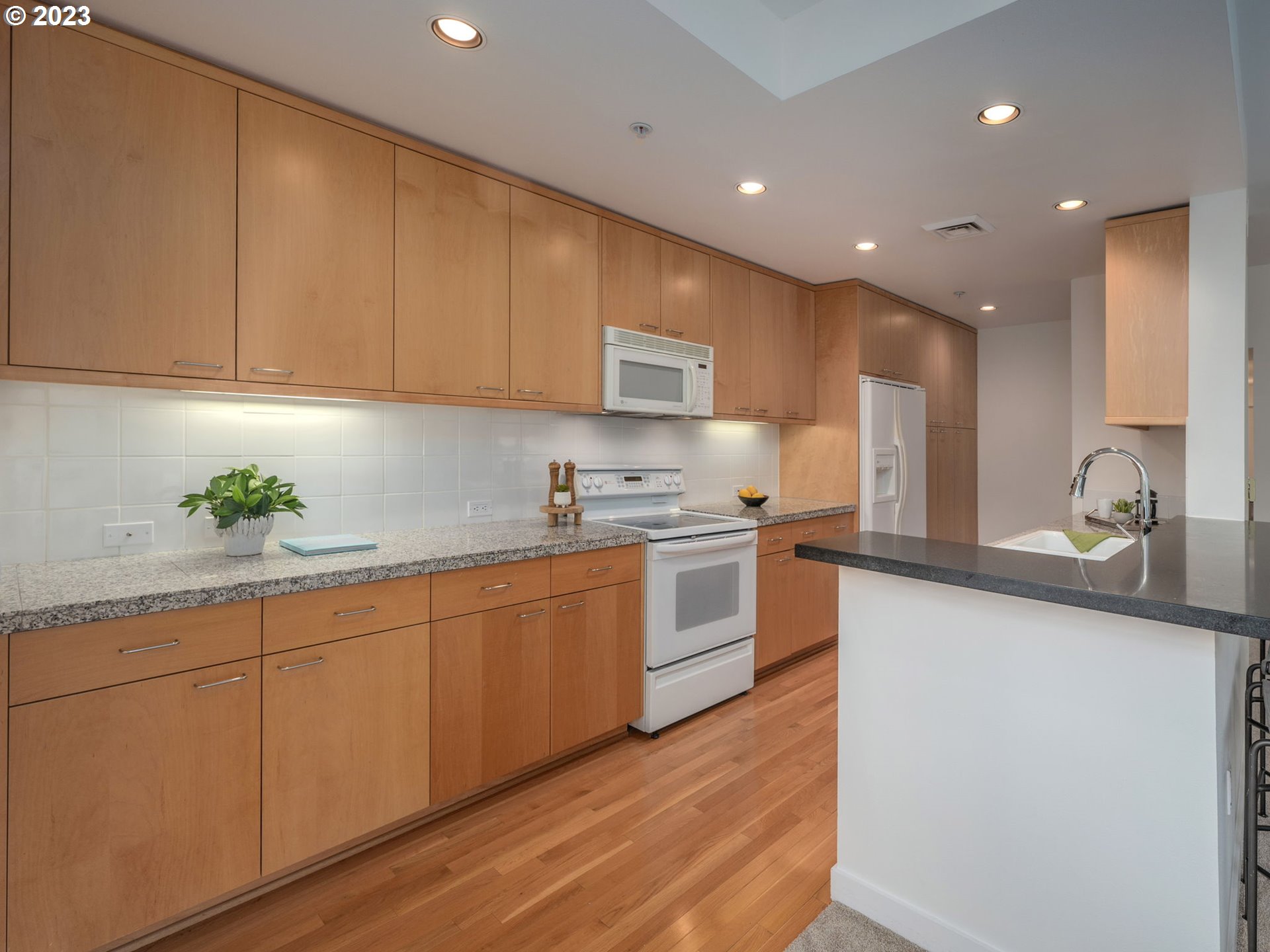 2445 Northwest Westover Road, Unit 314 Portland, OR 97210 - Photo 10 of 32 a kitchen with granite countertop white cabinets and white appliances