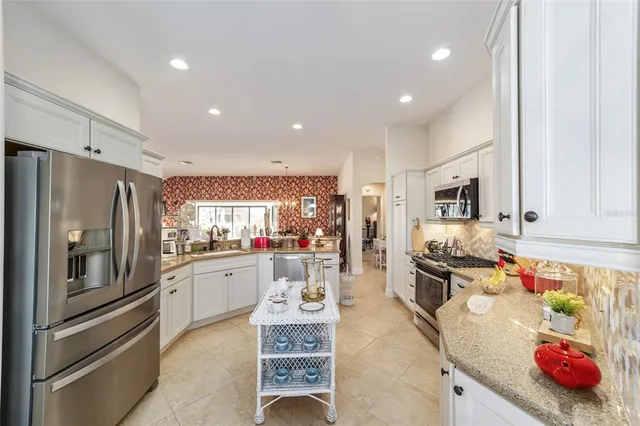 a kitchen with stainless steel appliances granite countertop a refrigerator sink and stove