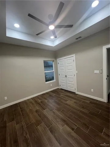 an empty room with wooden floor cabinet and windows