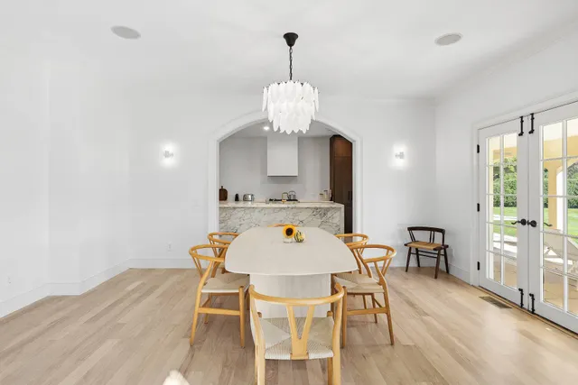 a dining room with wooden floor a chandelier a wooden table and chairs