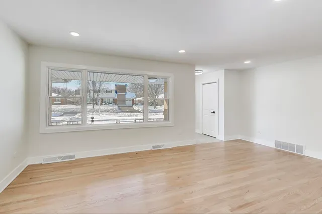 an empty room with wooden floor and a large window