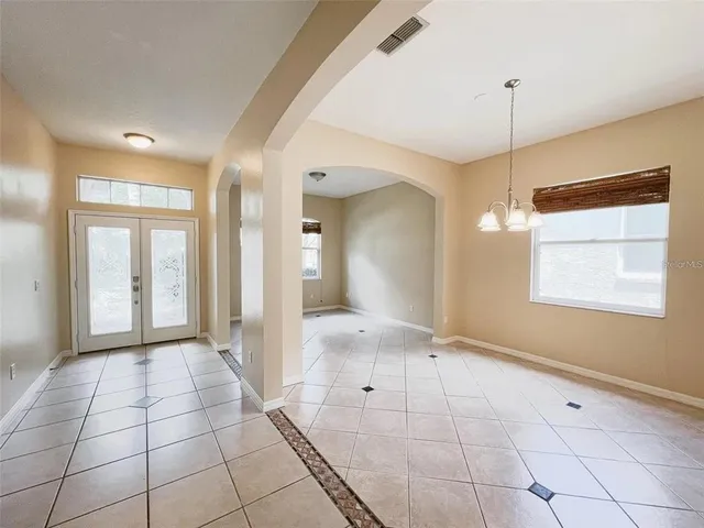 a view of an empty room with window and chandelier fan