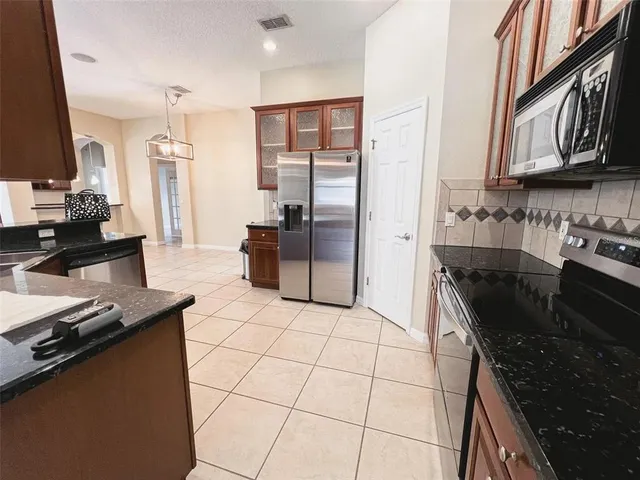 a kitchen with stainless steel appliances granite countertop a stove refrigerator and a sink