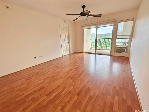 a view of empty room with wooden floor and fan