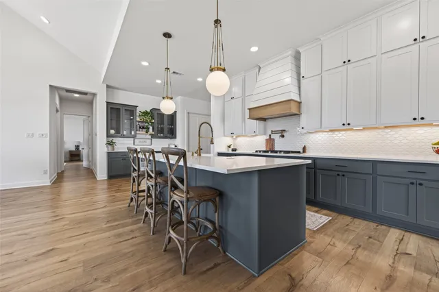 a kitchen with stainless steel appliances kitchen island granite countertop a table chairs and a white cabinets