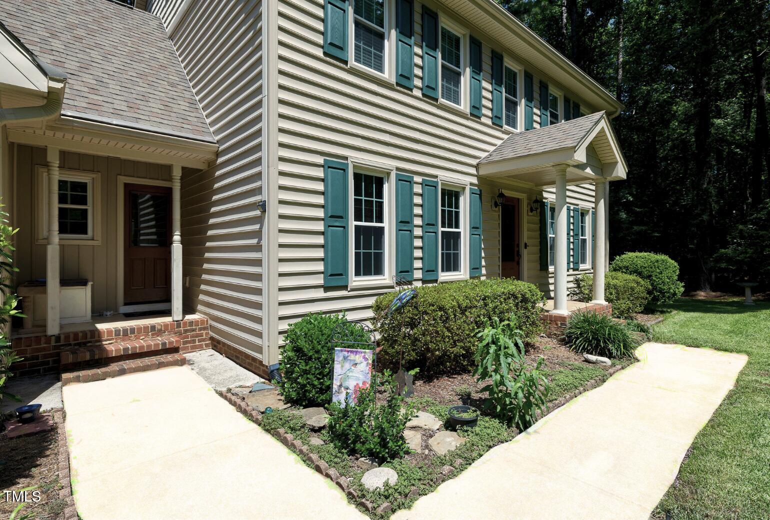 6309 Windy Ridge Court Raleigh, NC 27606 - Photo 45 of 53 a view of a white house with potted plants and a large tree