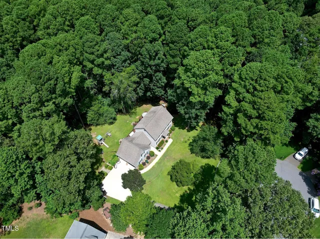 an aerial view of residential house with outdoor space and trees all around