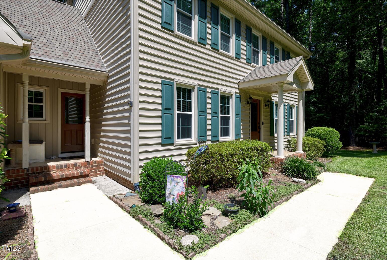 6309 Windy Ridge Court Raleigh, NC 27606 - Photo 4 of 53 a view of a white house with potted plants and a large tree