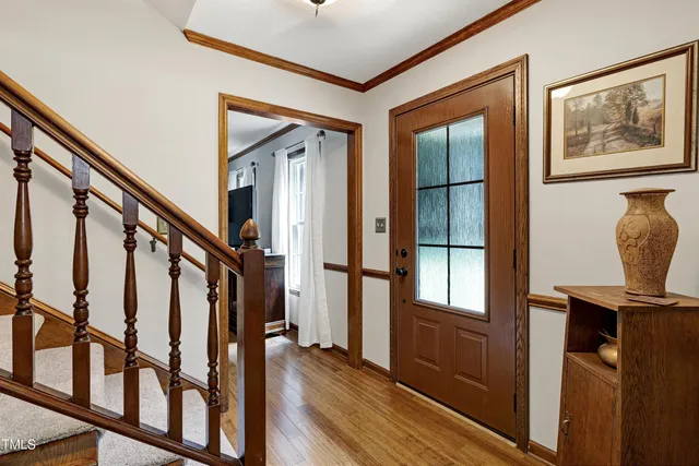 a view of a white house with potted plants and a large tree