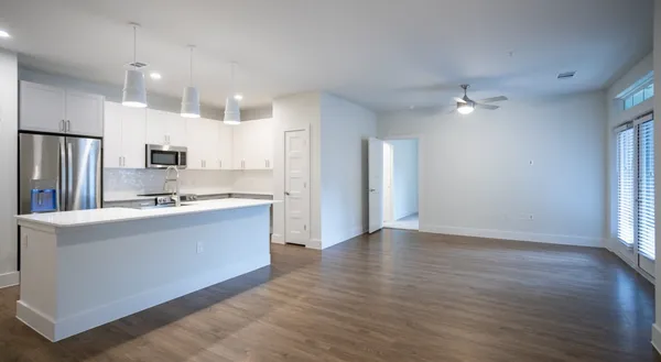 a large kitchen with stainless steel appliances a large counter top a sink a refrigerator and a window