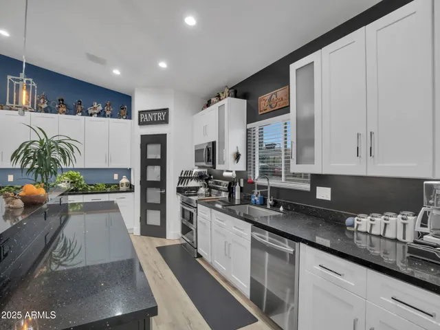 a kitchen with stainless steel appliances a white table chairs in it and wooden floor